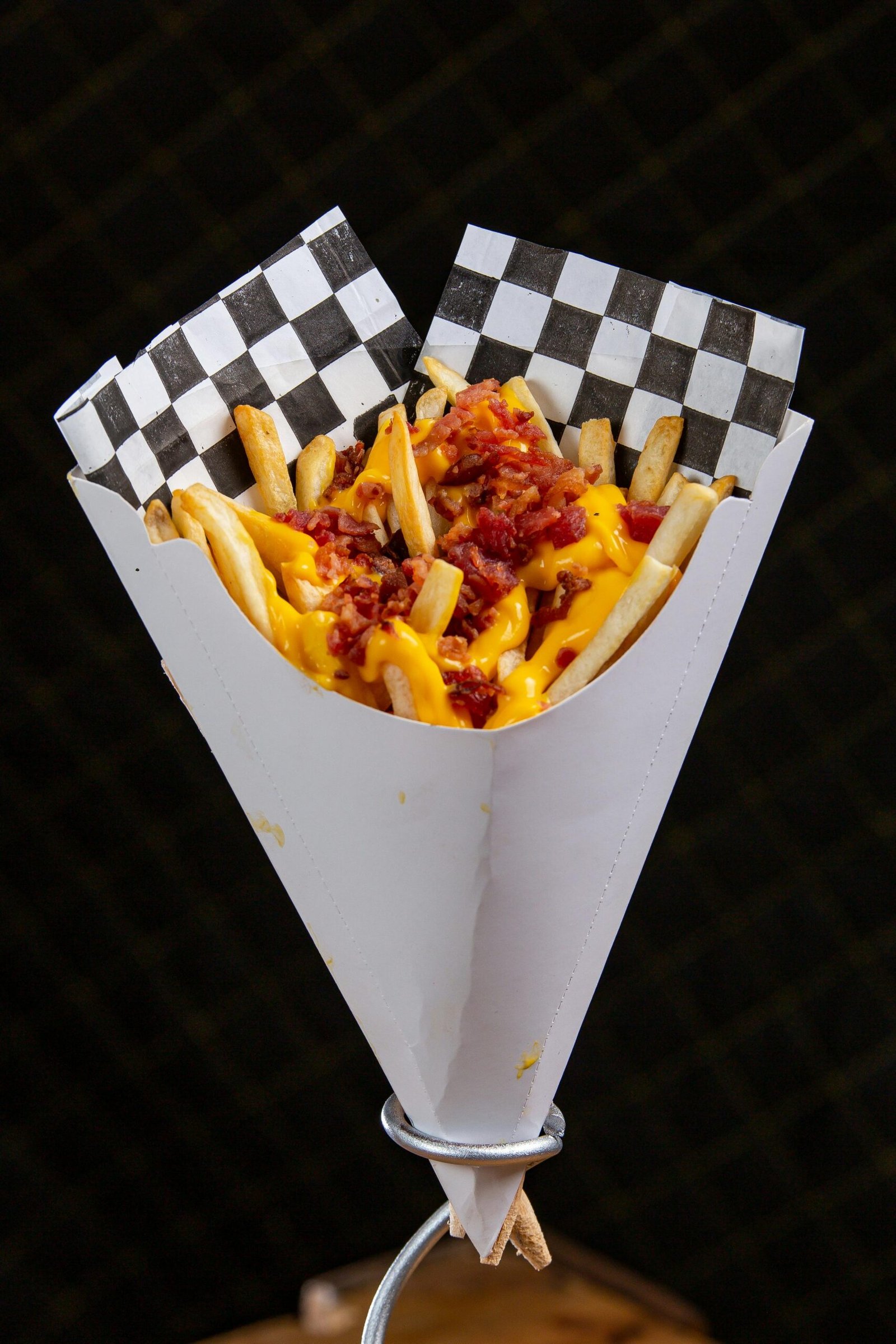 Delicious paper cone of fries topped with melted cheese and crispy bacon bits.