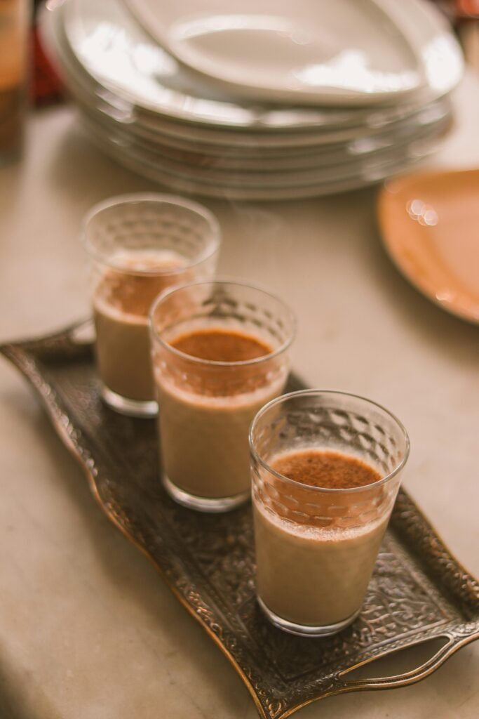 Three glasses of chai tea served on an elegant tray in warm afternoon light, perfect for a cozy setting.